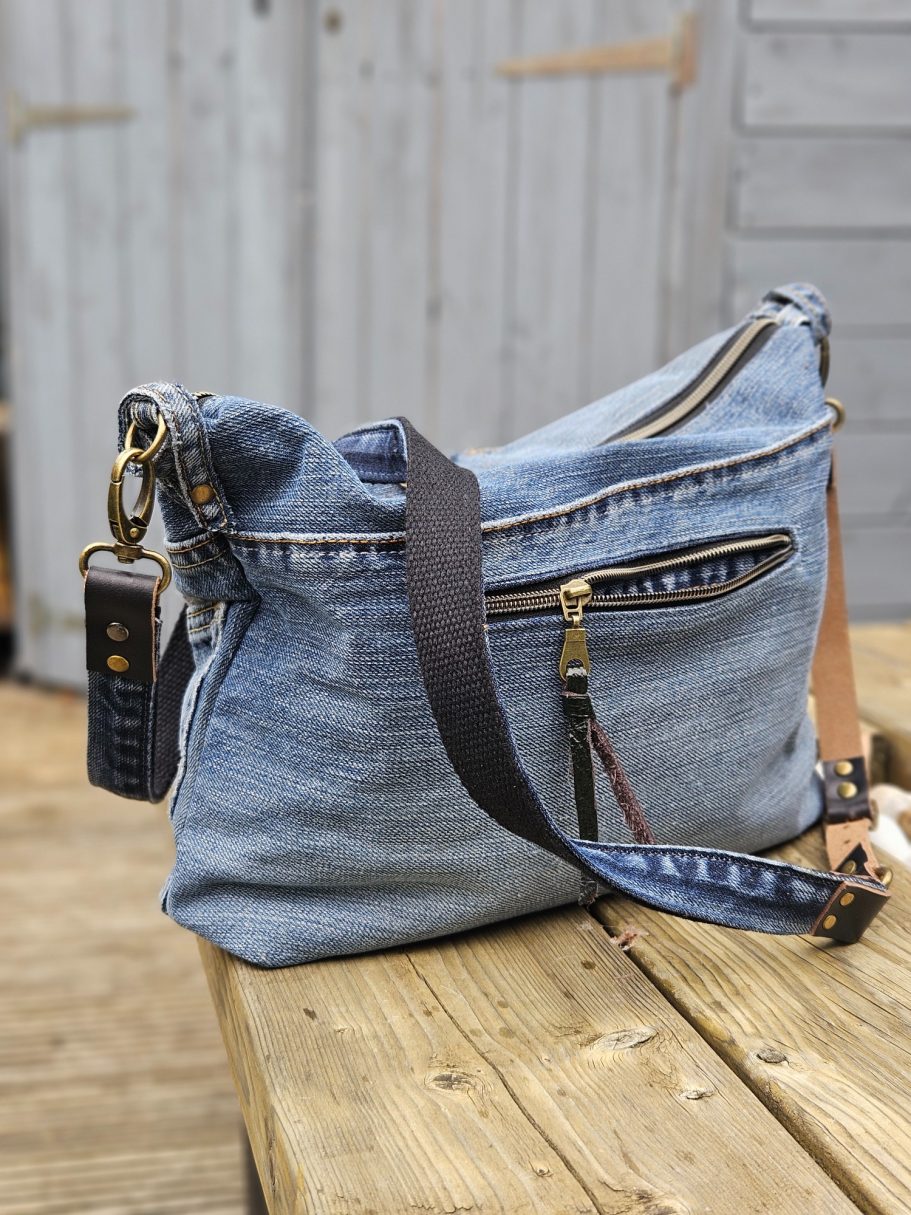 Denim Crossbody Bag Reclaimed denim crossbody bag with strap, showing original jeans pockets, zip detail and textured blue denim.