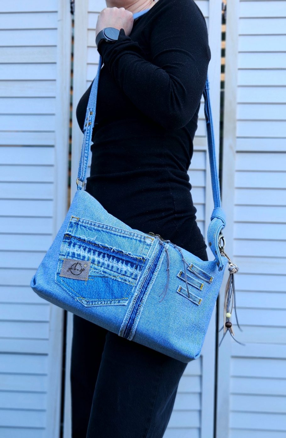 Light Denim Crossbody Bag With Pockets Light denim crossbody bag worn on the shoulder showing everyday size and fit