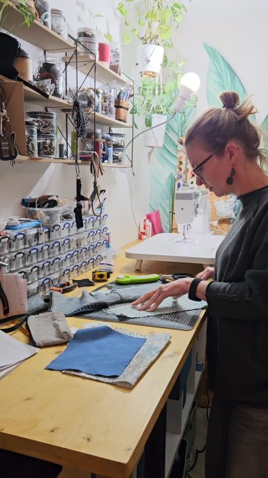 Behind the Making Gabus81 maker working at a sewing table with denim pieces for handmade upcycled bags