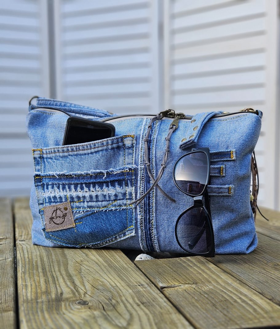 Light Denim Crossbody Bag With Pockets Side view of light denim crossbody bag with double zip closure and front pocket detail