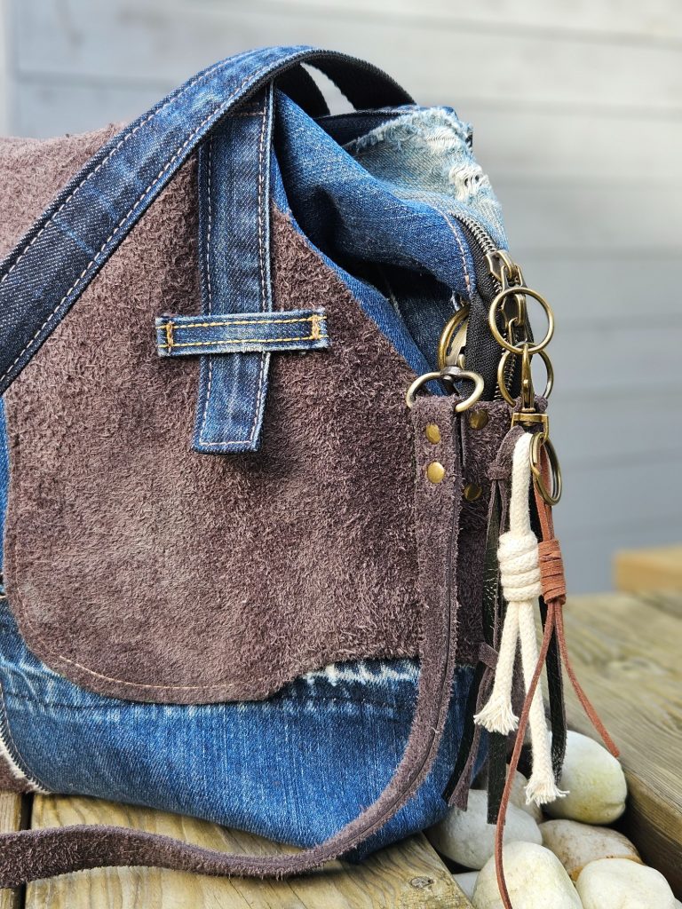 Brown and blue bag with a suede front and denim accents, featuring decorative straps.