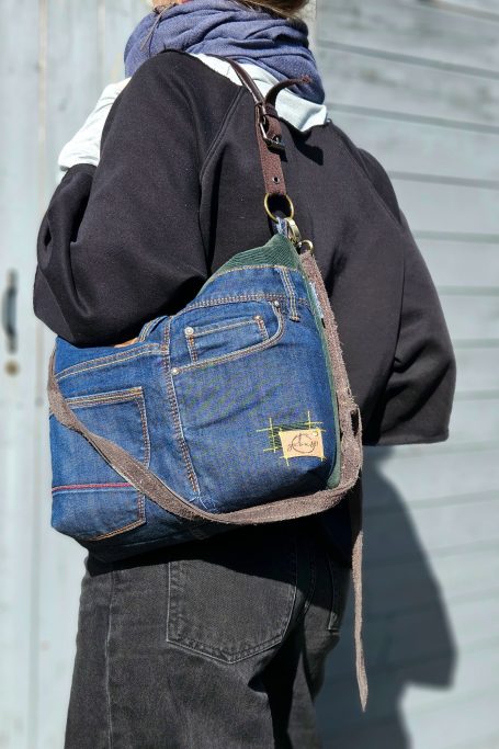 Blue Denim Crossbody Bag Blue denim crossbody bag worn on shoulder with patchwork denim design and practical everyday size