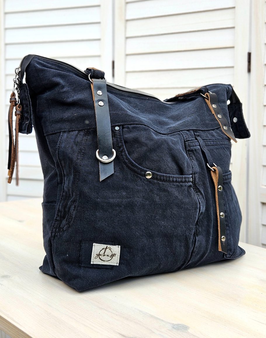 Just added Back view of a black upcycled denim shoulder bag with original jeans pocket, zip detail and leather accents