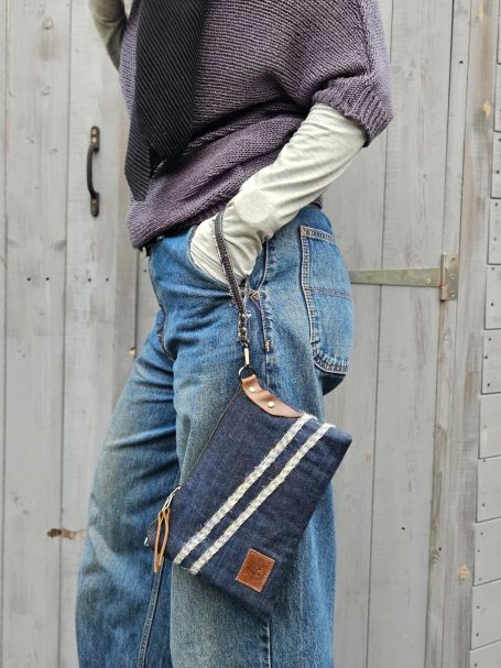 Denim Clutch Pouch Denim clutch pouch held in hand with slim shape and wrist strap detail